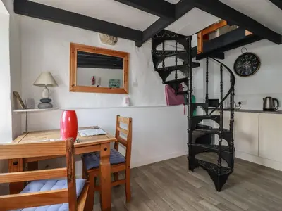 a room with a desk and a spiral staircase at Chy Rani in Portmellon