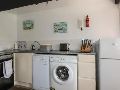 a kitchen with a washing machine and a washer at Chy Rani in Portmellon