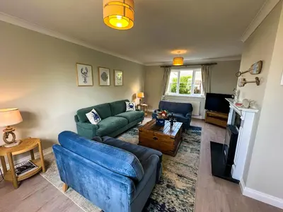 a living room with two blue couches and a tv at Chestnut House in Saint Columb Minor