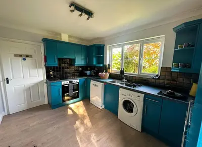 a kitchen with blue cabinets and a washer and dryer at Chestnut House in Saint Columb Minor