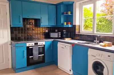 a kitchen with blue cabinets and a washer and dryer at Chestnut House in Saint Columb Minor