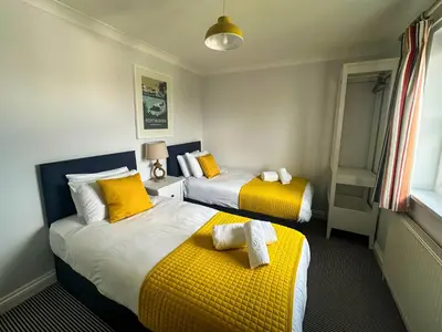 two beds in a room with yellow and white at Chestnut House in Saint Columb Minor