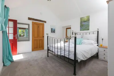 a bedroom with a bed and a red door at Pilgrims Barn in Hayle