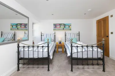 two twin beds in a room with a mirror at Pilgrims Barn in Hayle