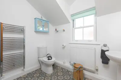 a bathroom with a toilet and a sink and a window at Pilgrims Barn in Hayle