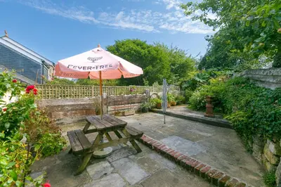a picnic table and an umbrella in a garden at Pilgrims Barn in Hayle