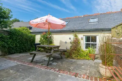 a picnic table with an umbrella in front of a house at Pilgrims Barn in Hayle