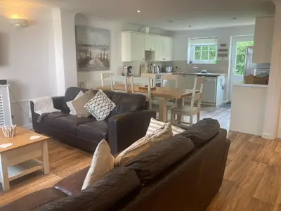 a living room with a brown couch and a kitchen at Eventide in Newquay