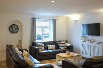 a living room with two leather couches and a tv at Eventide in Newquay