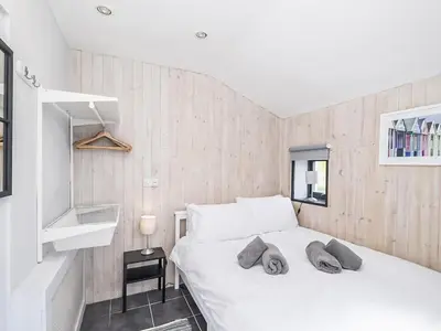 a bedroom with a white bed and a wooden wall at The Light House in Gwithian