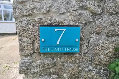 a light house sign on a stone wall at The Light House in Gwithian