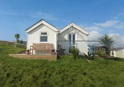 a white house with a bench in the grass at Wee Cott in Hayle