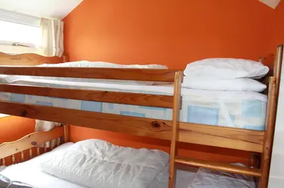 two bunk beds in a room with an orange wall at Wee Cott in Hayle