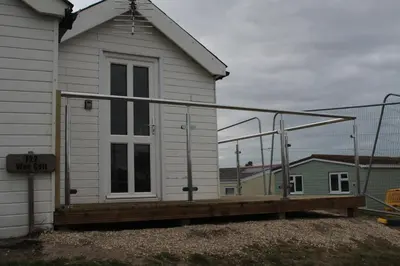 a house with a porch with a railing on it at Wee Cott in Hayle