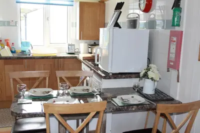 a kitchen with a table with chairs and a microwave at Wee Cott in Hayle