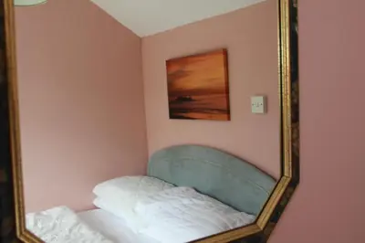 a mirror on a wall with a bed in a room at Wee Cott in Hayle