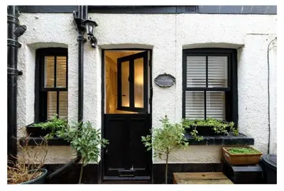 a house with a black door and two windows at Chy Pyscador in Looe