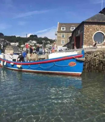 a blue boat is docked next to a pier at Chy Pyscador in Looe