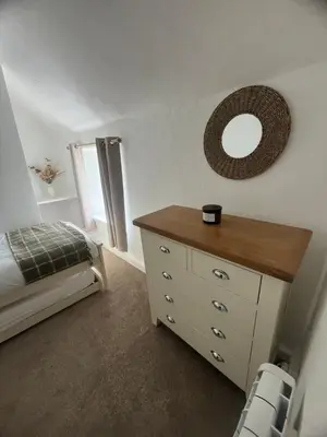 a bedroom with a bed and a dresser with a mirror at 1 Carnebone Cottages in Porkellis