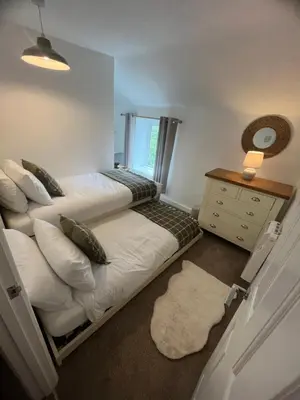 a bedroom with two beds and a dresser and a window at 1 Carnebone Cottages in Porkellis