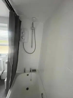 a white bathroom with a shower and a toilet at 1 Carnebone Cottages in Porkellis