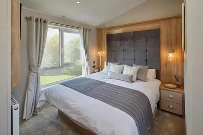a bedroom with a large bed with a window at Pool - Fireplace - 2Br Lodge - PetsOK - Parking in Newquay