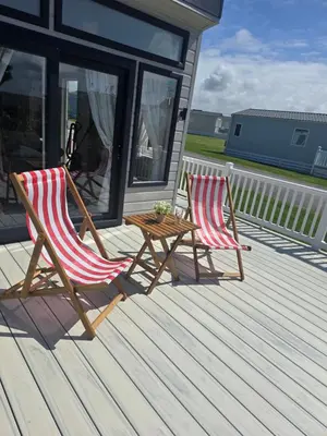 two rocking chairs and a table on a porch at Pool - Fireplace - 2Br Lodge - PetsOK - Parking in Newquay