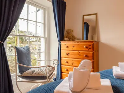 a bedroom with a bed and a dresser and a mirror at Holiday Home Elm Cottage by Interhome in Mevagissey