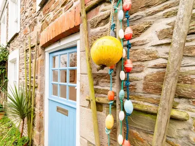 a building with a blue door and a bunch of beads at Holiday Home Elm Cottage by Interhome in Mevagissey