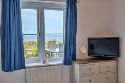a room with a window with blue curtains and a television at Finest Retreats - Blue Horizon in St Ives