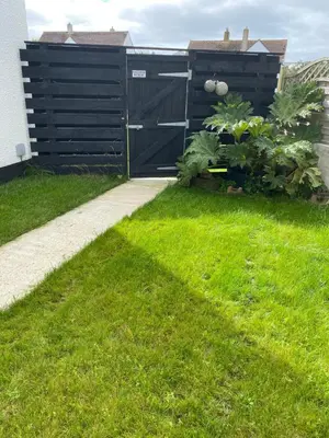 a garden with a black gate and green grass at Seashells in Padstow