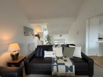 a living room with a black leather couch with pillows at Newly renovated beach house on the coast in Saint Columb Minor