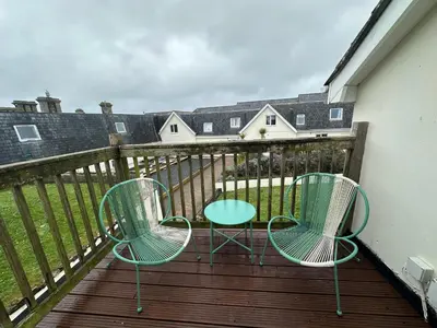 two chairs and a table on a deck at Newly renovated beach house on the coast in Saint Columb Minor
