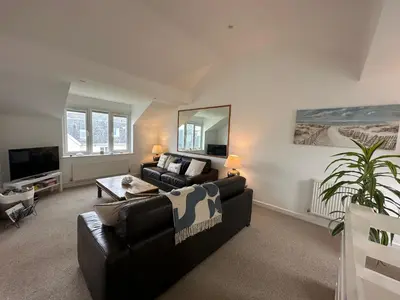 a living room with a black couch and a mirror at Newly renovated beach house on the coast in Saint Columb Minor