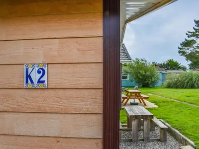 a sign on the side of a house with a picnic table at K2 Cosy Lodge in Padstow