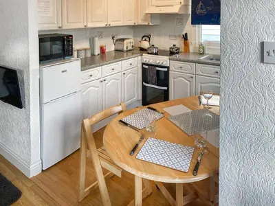 a kitchen with a wooden table and white appliances at K2 Cosy Lodge in Padstow