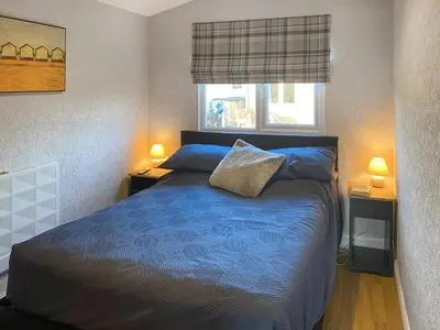 a bedroom with a blue bed and a window at K2 Cosy Lodge in Padstow