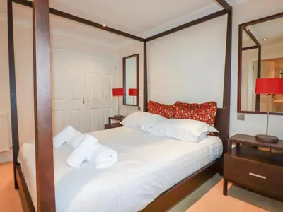 a bedroom with a large white bed with a mirror at Clematis - Lodge 16 in Wadebridge