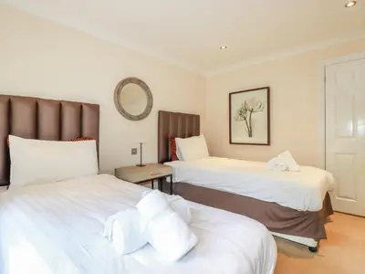 a bedroom with two beds and a mirror at Clematis - Lodge 16 in Wadebridge