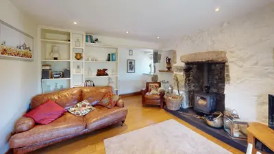 a living room with a leather couch and a fireplace at 1 St Ives Higher Ayr Cottage in St Ives