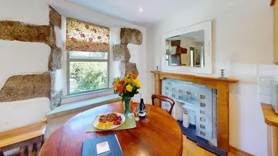 a dining room with a table with a vase of flowers at 1 St Ives Higher Ayr Cottage in St Ives