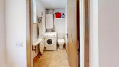 a small bathroom with a toilet and a washing machine at 1 St Ives Higher Ayr Cottage in St Ives