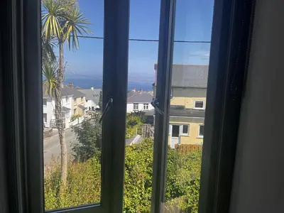 a window with a view of a palm tree at 1 St Ives Higher Ayr Cottage in St Ives