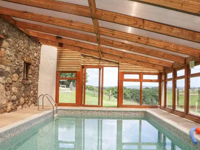 an indoor pool in a house with wooden ceilings and windows at Skiber Coombe in Callington