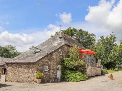 a stone building with a roof with an umbrella at Skiber Coombe in Callington