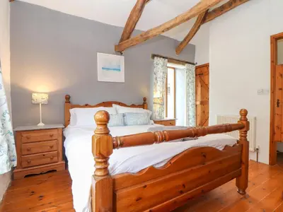 a bedroom with a wooden bed and a window at Skiber Long in Callington