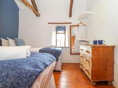 a bedroom with two beds and a wooden dresser at Skiber Long in Callington