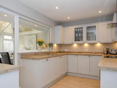 a kitchen with white cabinets and a sink at Coastal Haven in Bude