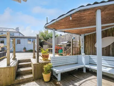 a wooden gazebo with a bench on a deck at Coastal Haven in Bude