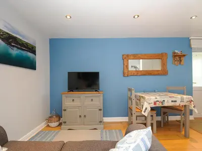 a room with a blue wall with a table and a tv at Coastal Haven in Bude